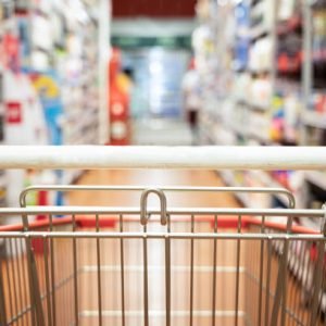 Perspective view of shopping trolley cart with modern supermarket aisle blurred background